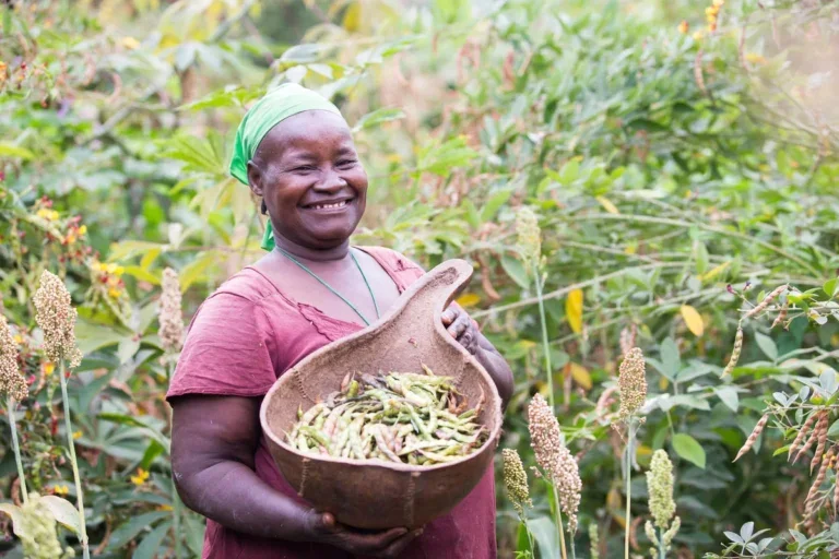woman smiling and holding a bowl of vegetables in a field