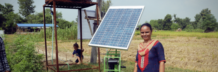 woman standing in front of a solar panel in an open field